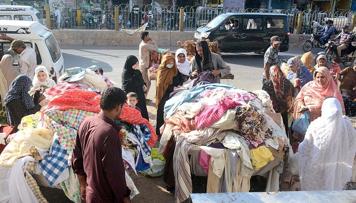 Women selecting used clothes at a roadside stall in Karachi on May 16, 2023. — APP