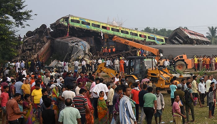People stand next to damaged coaches after two passenger trains collided in Balasore district in the eastern state of Odisha, India, June 3, 2023. — Reuters