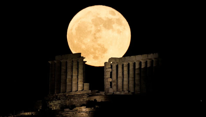 The full strawberry moon rises behind the Temple of Poseidon at Cape Sounion near Athens, Greece, in June 2022.—Reuters