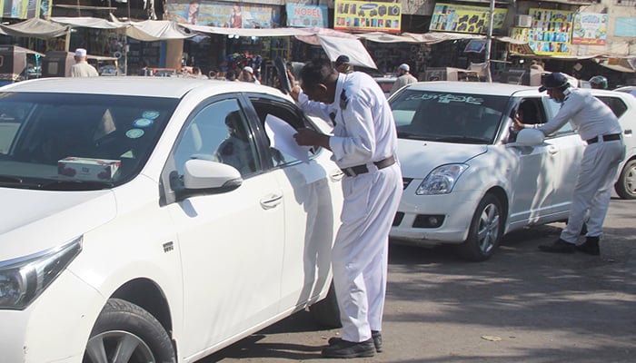 A traffic police official issuing a challan to a vehicle owner for violating the traffic rules in Karachi on May 2, 2023. — Online
