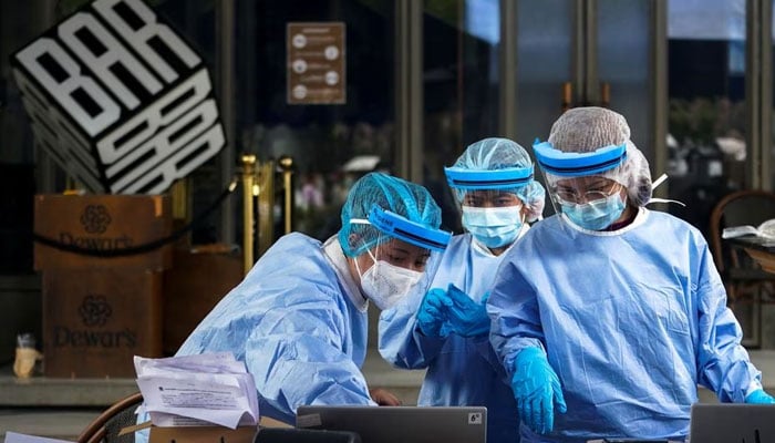 Healthcare workers work in front of a closed bar and take nasal swab samples from a local resident for COVID-19. — Reuters/File