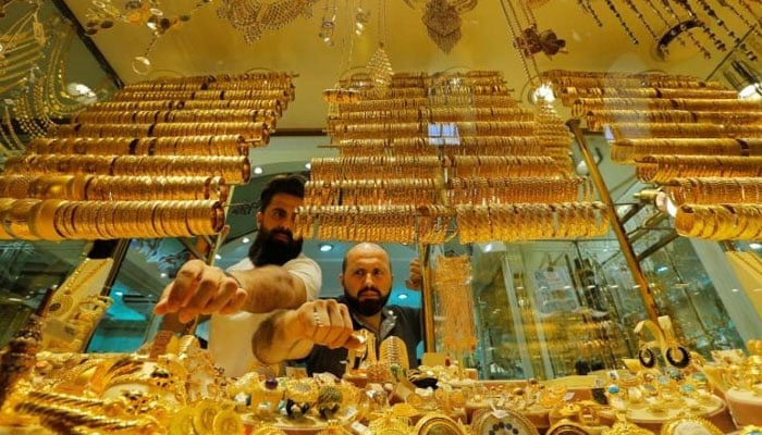 Salesmen rearrange glittering gold ornaments inside a showcase at a jewellers shop. — Reuters/File