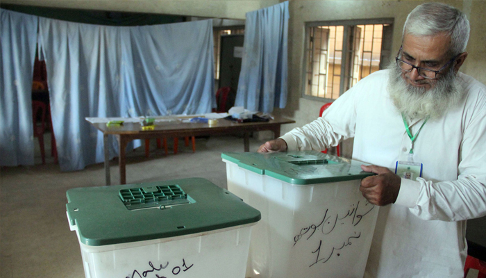 A worker of Election Commission of Pakistan (ECP) finalizing the arrangements at a polling station in Karachi on May 6, 2023. — Online