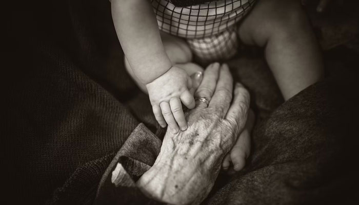 A representational image of the hands of a baby and an old person. — Unsplash/File
