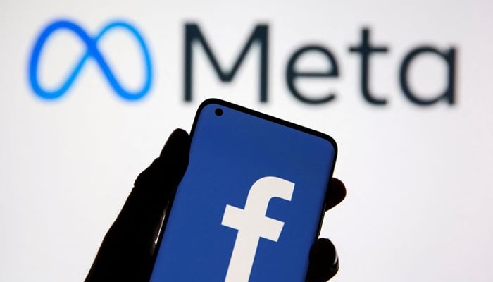A smartphone with Facebooks logo is seen in front of displayed Facebooks new rebrand logo, Meta in this illustration. — Reuters/File