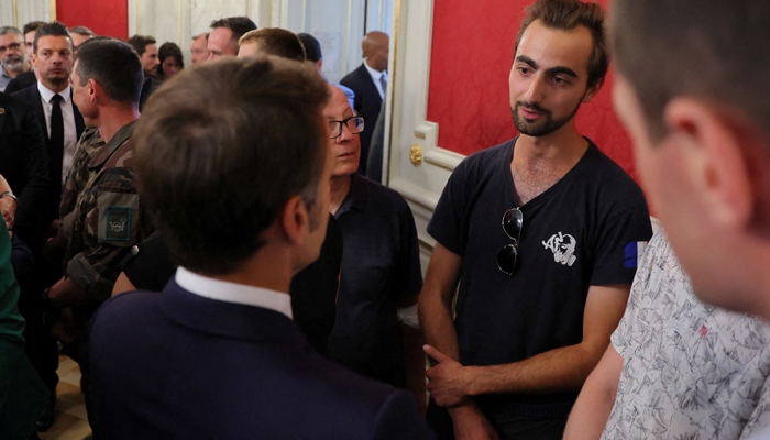 President Emmanuel Macron (L) talks with Henri (R), the 24-year-old backpack hero, who suffered minor stab wounds. — AFP