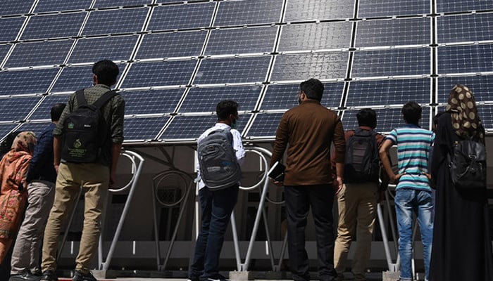 Students look at the facade of a building made with solar panels during its inauguration at the University of Engineering and Technology in Lahore on October 12, 2020. — AFP