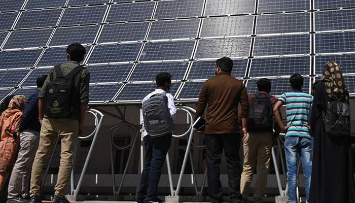 Students look at the facade of a building made with solar panels during its inauguration at the University of Engineering and Technology in Lahore on October 12, 2020. — AFP