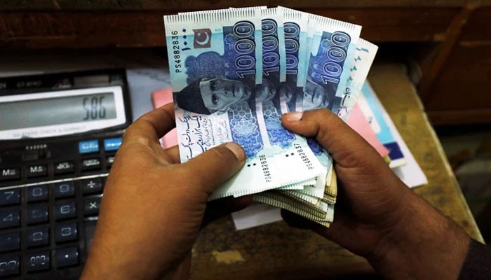 A trader counts Pakistani rupee notes at a currency exchange booth in Peshawar, on December 3, 2018. — Reuters