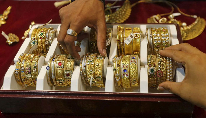 A salesman helps a customer (R) to select gold bangles at a jewelry showroom in Mumbai, India, May 21, 2015. — Reuters