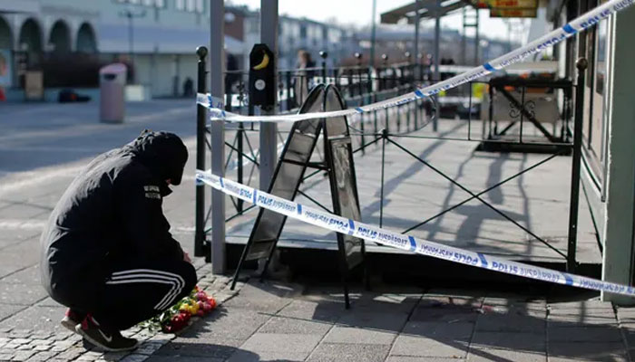 A man laying flowers at the scene of a fatal shooting in Gothenburg, Sweden, in March 2015.—EPA/file