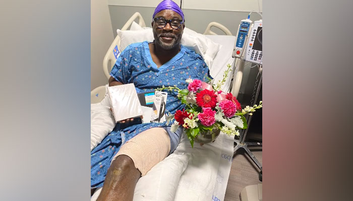53-year-old Donnie Adams can be seen in a hospital bed with his injured leg and flowers after undergoing his surgery. — Screengrab/YouTube/NBC News