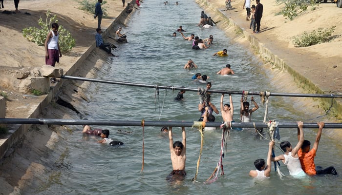 People bathing in a canal to cool themselves during extreme heat wave in Karachi on May 11, 2022. — Online