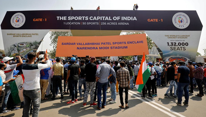 Workers install a hoarding renaming the worlds largest cricket stadium, previously known as the?Motera Stadium, after Prime Minister Narendra Modi, as fans wait to enter before the start of the third test match between India and England in Ahmedabad, India, February 24, 2021. — Reuters