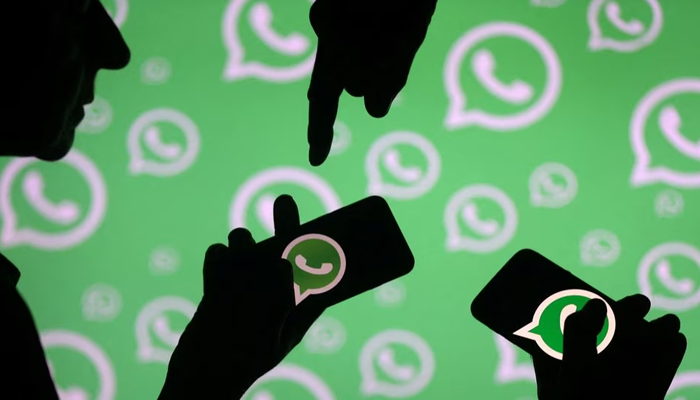 Men pose with smartphones in front of displayed WhatsApp logo in this illustration September 14, 2017.