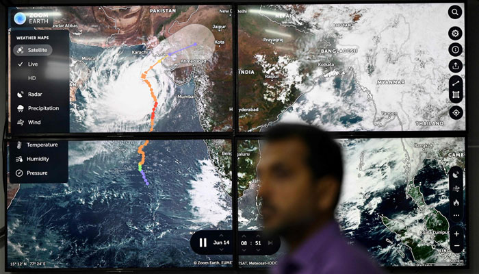نیشنل ڈیزاسٹر مینجمنٹ اتھارٹی (این ڈی ایم اے) کا ایک اہلکار 14 جون 2023 کو اسلام آباد میں این ڈی ایم اے مانیٹرنگ روم میں طوفان بِپرجوئے کی سیٹلائٹ تصاویر دکھاتے ہوئے ٹی وی اسکرین کے سامنے کھڑا ہے۔ — اے ایف پی