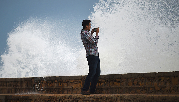 A man takes photos of high tides at a beach before the due onset of cyclone Biparjoy, in Karachi on June 13, 2023. — AFP