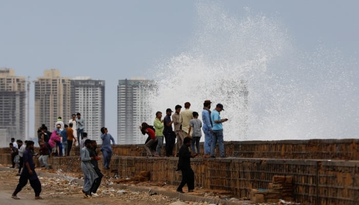 13 جون، 2023 کو کراچی، پاکستان میں کلفٹن بیچ پر بحیرہ عرب کے اوپر سمندری طوفان بپرجوئے کی آمد سے پہلے لوگ بڑھتی ہوئی لہروں کے قریب جمع ہیں۔ — رائٹرز