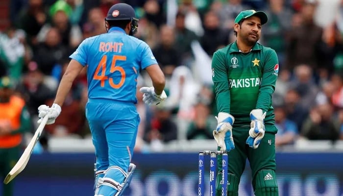 Former Pakistan captain Sarfaraz Ahmed reacts amid a Pakistan vs India match while Indian batter Rohit Sharma walks back to the crease. -- AFP/File