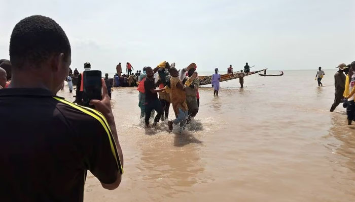 A man takes a picture as the body of one of the victims of a boat accident is being retrieved from the boat in Kebbi, Nigeria. — Reuters/File