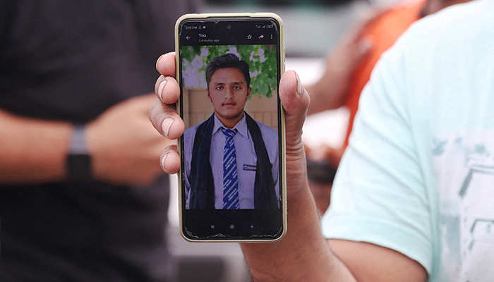 Pakistani Hassan Ali, who says his brother Fahad, 21, was onboard a boat with migrants that capsized at open sea off Greece, shows a photo of his brother in front of a migrant camp in Malakasa, near Athens, Greece, June 16, 2023. — Reuters