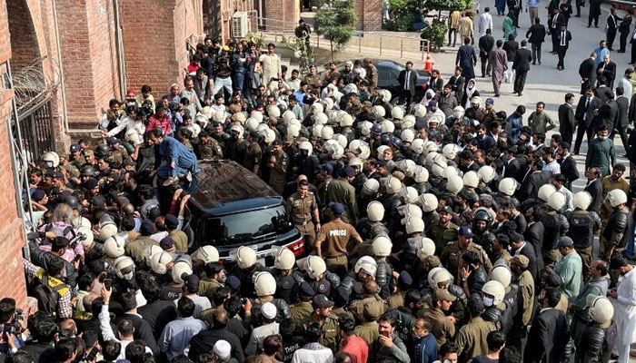 Police officers escort the vehicle of the deposed prime minister as he appears at the district high court in Lahore, on March 21, 2023. — Reuters