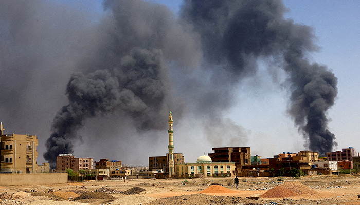 A man walks while smoke rises above buildings after aerial bombardments during clashes between the paramilitary Rapid Support Forces and the army in Khartoum North, Sudan, May 1, 2023. — Reuters