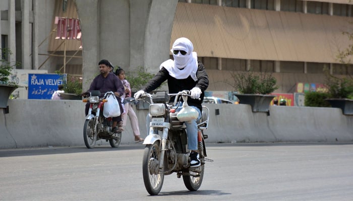A biker covers his face with a piece of cloth to protect himself from heatwave in Rawalpindi on June 10, 2023. — Online
