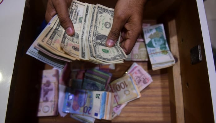 A dealer counts US dollars at a money exchange market in Karachi on January 27, 2023. — AFP