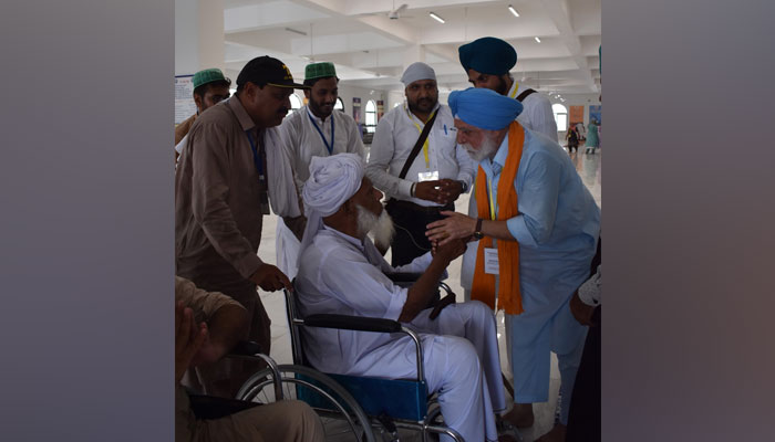 Resident of Okara Taj Muhammad meets one of the family members of Sardar Manohar Singhs family. — Twitter/@PmuKartarpur