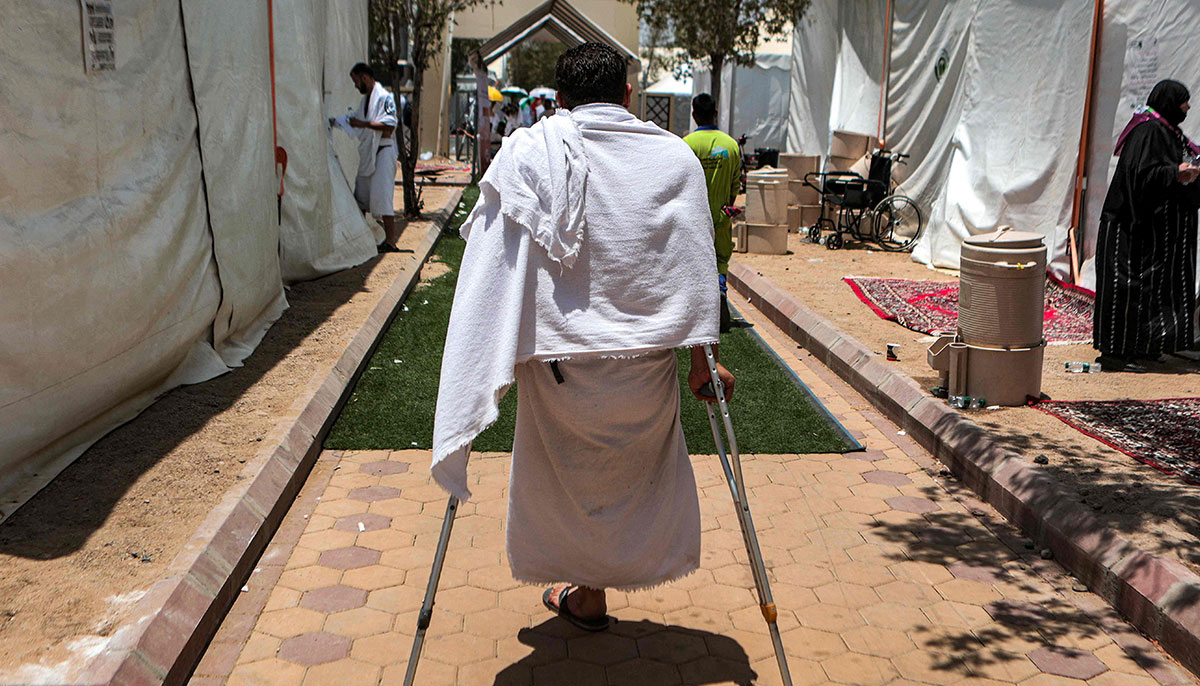 A Syrian amputee walks with crutches outside tents near Mount Arafat on June 27, 2023. — AFP