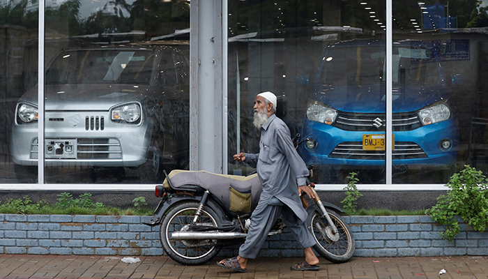 A man walks past a Suzuki outlet, displaying cars in Karachi, Pakistan, July 27, 2022. — Reuters