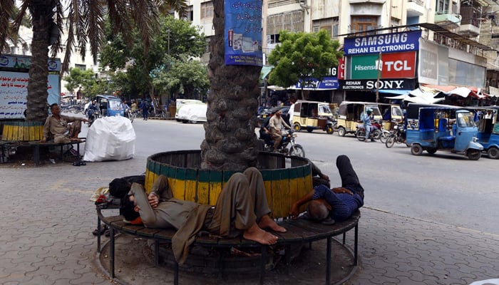 Karachiites nap under the shadow of a tree during a hot day at the Regal Chowk in Karachi on Friday, June 23, 2023. — PPI