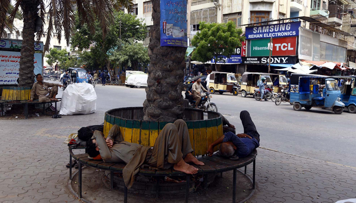 Karachiites nap under the shadow of a tree during a hot day at the Regal Chowk in Karachi on Friday, June 23, 2023. — PPI
