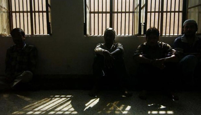 اس نامعلوم تصویر میں تاریک لاک اپ کے اندر بیٹھے قیدی نظر آ رہے ہیں۔  — اے ایف پی/فائل