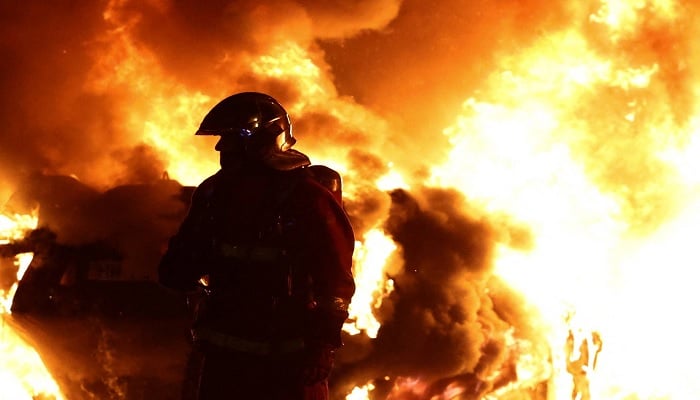 A firefighter stands in front of a burning vehicle during clashes between protesters and police, after the death of Nahel, a 17-year-old teenager killed by a French police officer during a traffic stop, in the Paris suburb of Nanterre, on Wednesday. — Reuters
