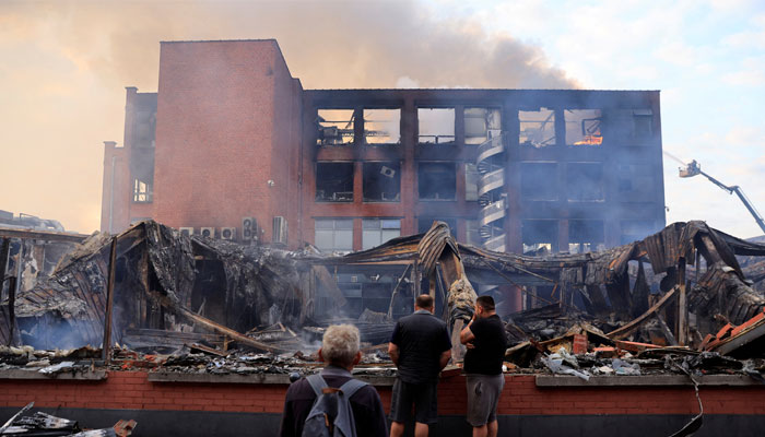 People look at a building of the Tessi group, burnt during night clashes between protesters and police, following the death of Nahel, a 17-year-old teenager killed by a French police officer in Nanterre during a traffic stop, at the Alma district in Roubaix, northern France, June 30, 2023. — Reuters