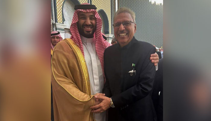 سعودی عرب کے ولی عہد محمد بن سلمان (بائیں) اور صدر ڈاکٹر عارف علوی مملکت میں ایک تقریب کے دوران ایک دوسرے سے مصافحہ کر رہے ہیں۔  — Twitter/@ArifAlvi