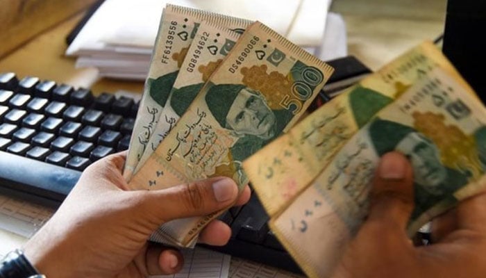 A man counts money at his shop in Karachi.— AFP/File