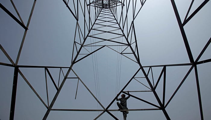 A worker of Peshawar Electric Supply Company (PESCO) climbs up a high-voltage pylon in Peshawar, August 7, 2017. — Reuters