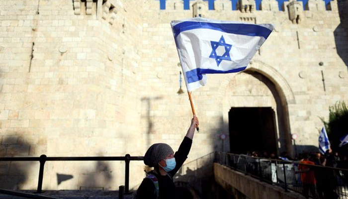 An Israeli woman holds a flag by Damascus gate just outside Jerusalems Old City June 15, 2021. — Reuters