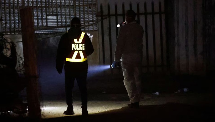 A police officer and a member of the forensic team inspect the scene of a suspected gas leak thought to be linked to illegal mining, in the Angelo shack settlement, near Boksburg on July 6, 2023. — Reuters