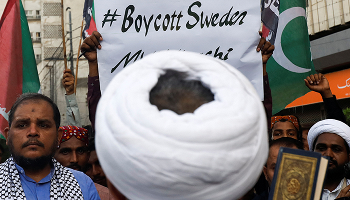 Muslims carry a poster, as they listen to the speech of a leader during a protest, to denounce the desecration of Quran outside a mosque in the Swedish capital Stockholm, in Karachi, on July 2, 2023. — Reuters