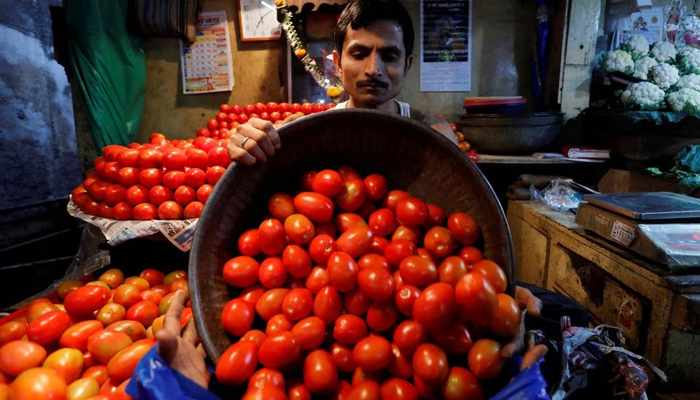 A vendor loads tomatoes in a bag for a customer at a wholesale vegetable market in Mumbai, India, March 14, 2018. — Reuters