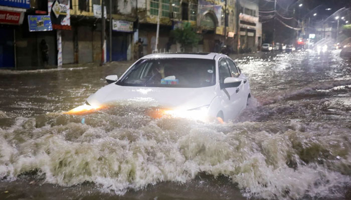 24 جولائی، 2022 کو کراچی، پاکستان میں مون سون کے موسم کے دوران شدید بارشوں کے بعد ایک گاڑی سیلاب زدہ سڑک کے ساتھ چل رہی ہے۔ - رائٹرز