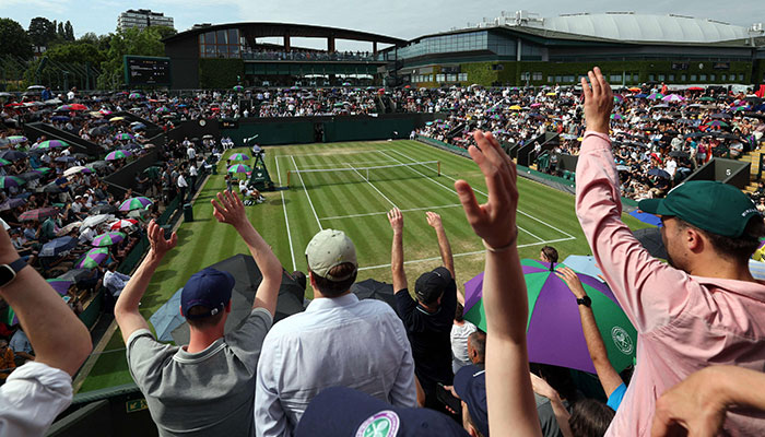 TOPSHOT - Spectators wave during the men's singles tennis match between Alejandro Davidovich Fokina of Spain and Holger Roon of Denmark on day six of the 2023 Wimbledon Championships at All England Tennis Club in Wimbledon, southwest London on July 8, 2023.— AFP