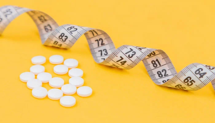 This image shows medicinal pills displayed next to a measuring tape. — Unsplash/File