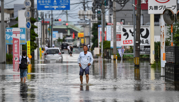 A man wades through a flooded street in the city of Kureme, Fukuoka prefecture, on July 10, 2023, after heavy rains hit wide areas of Kyushu island. — AFP