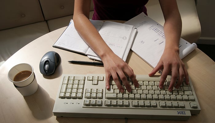 A woman works at her desk typing on a computer in this illustration picture taken January 9, 2005. — Reuters