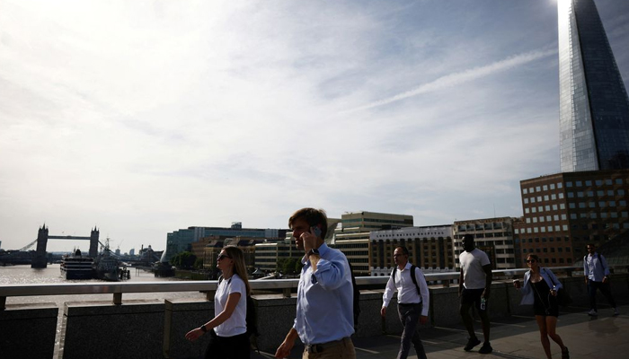 Commuters walk over London Bridge during warm weather in London, Britain, June 17, 2022.